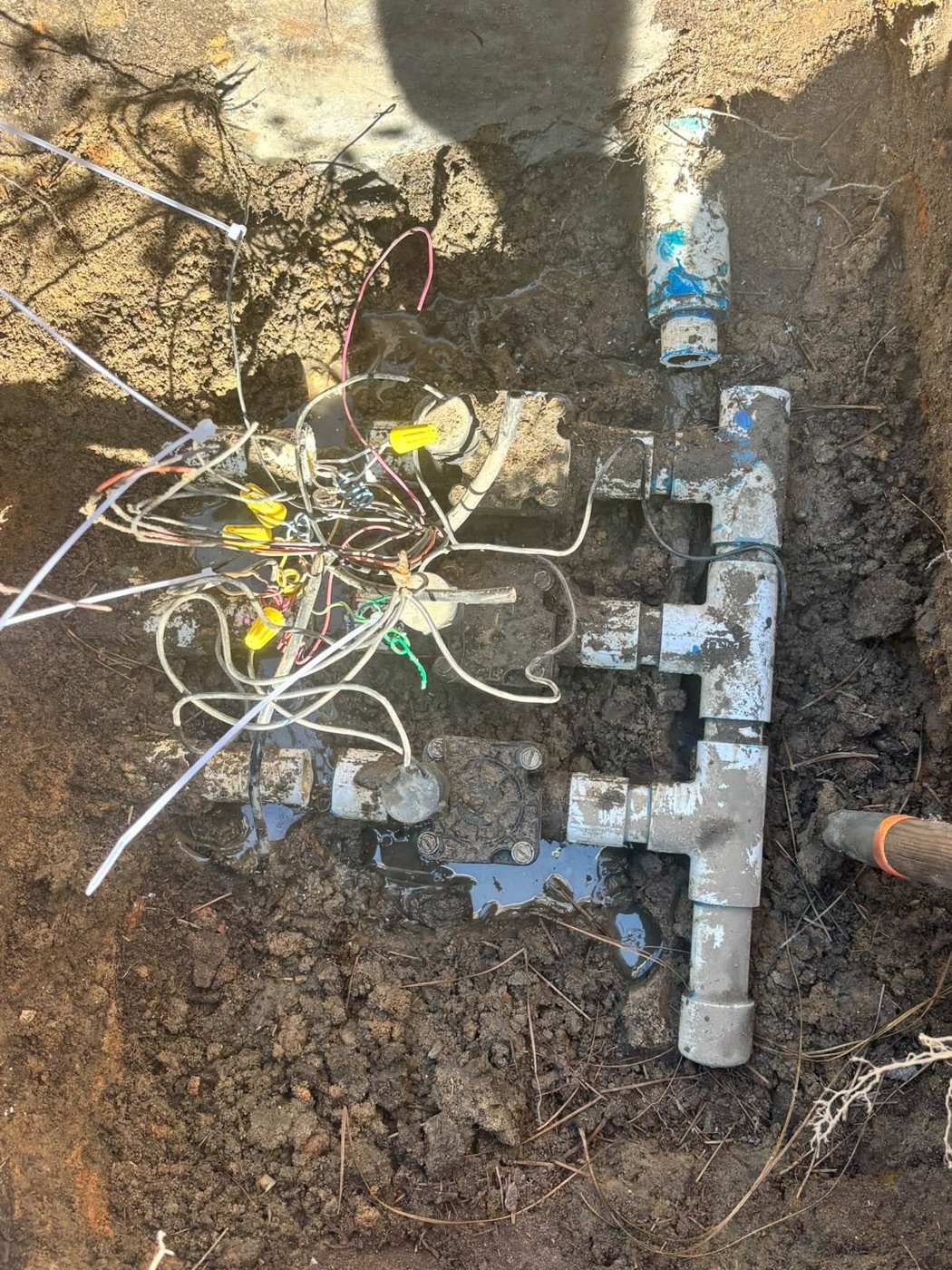 Before: three corroded sprinkler valves buried in mud with tangled, exposed wiring